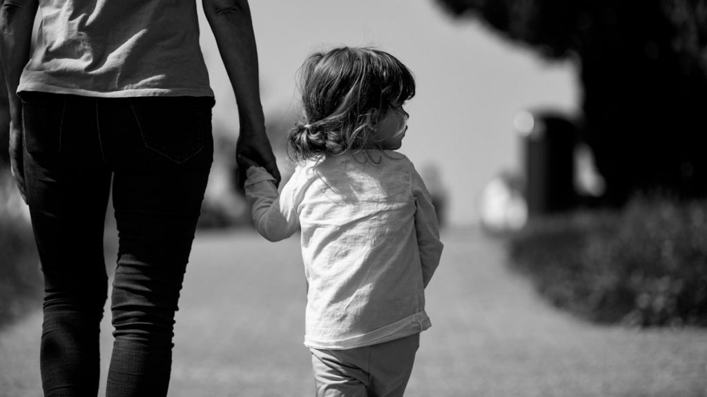 A woman holding the hand of a small child