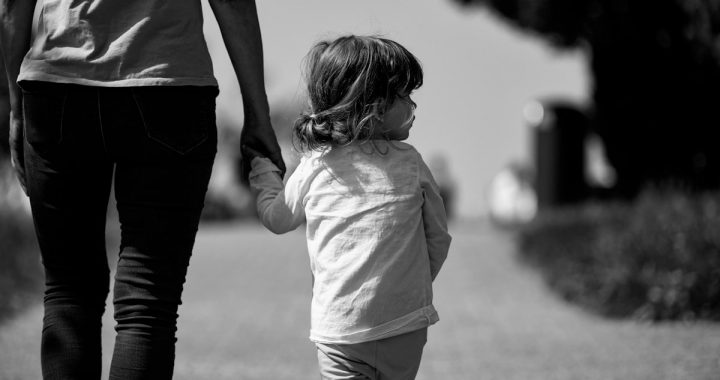A woman holding the hand of a small child