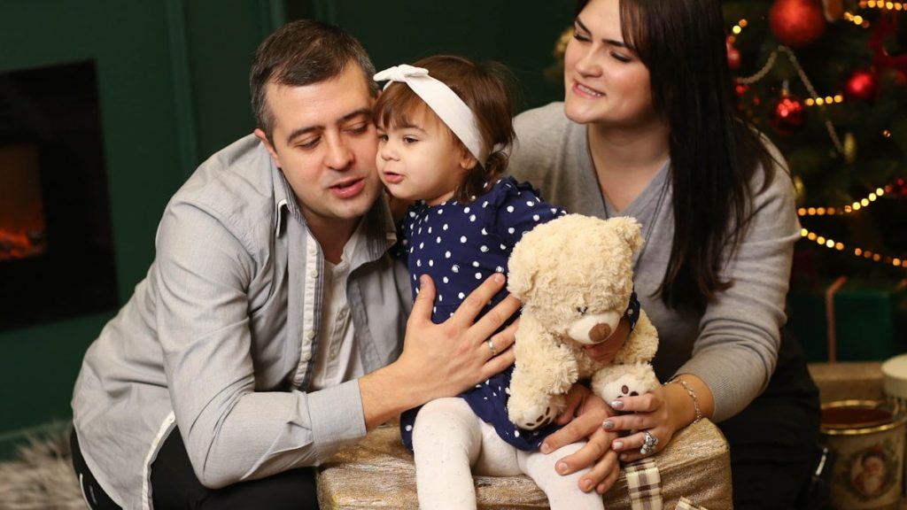 a man, woman and child sitting in front of a christmas tree