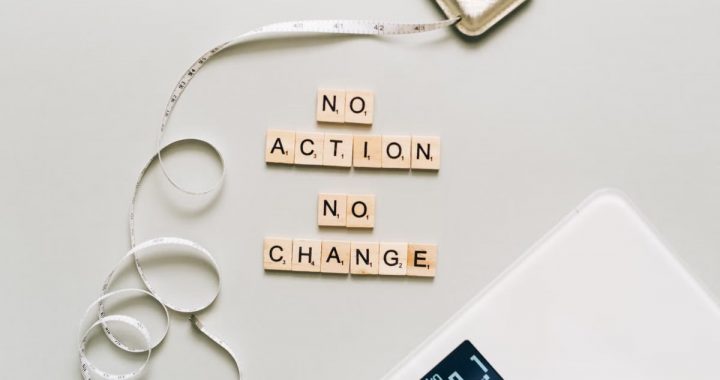 Motivational concept with scrabble tiles spelling no action no change alongside a measuring tape and scale.